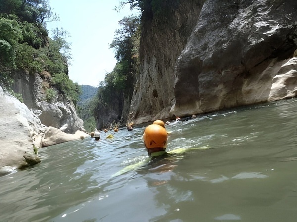 un grupo de personas nadando en un río con un casco amarillo