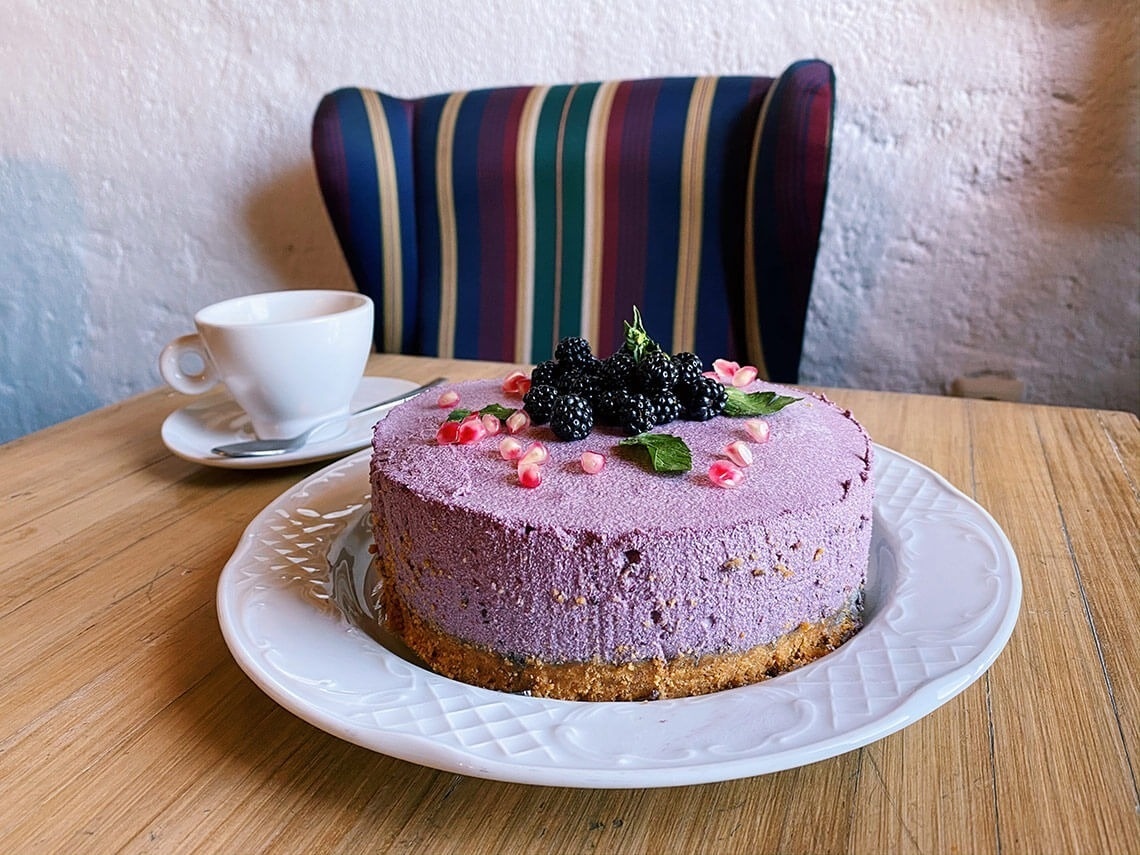 un pastel morado con moras y granadas está sobre un plato blanco