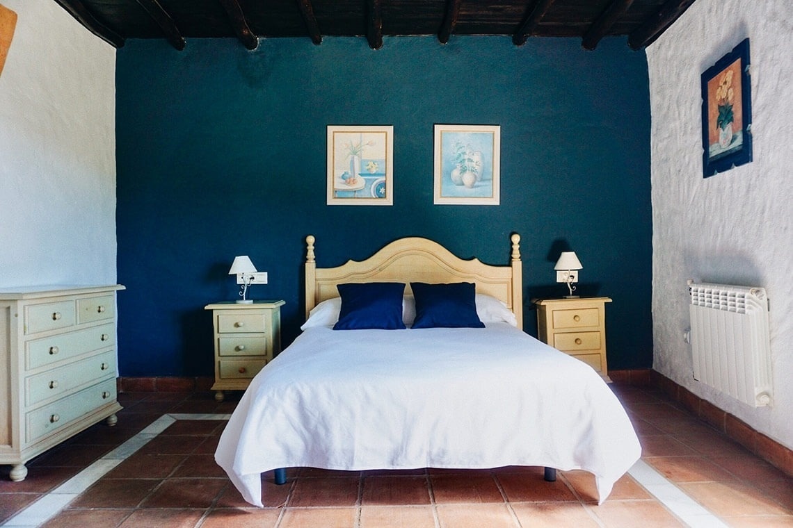 a bedroom with a blue wall and a white bed