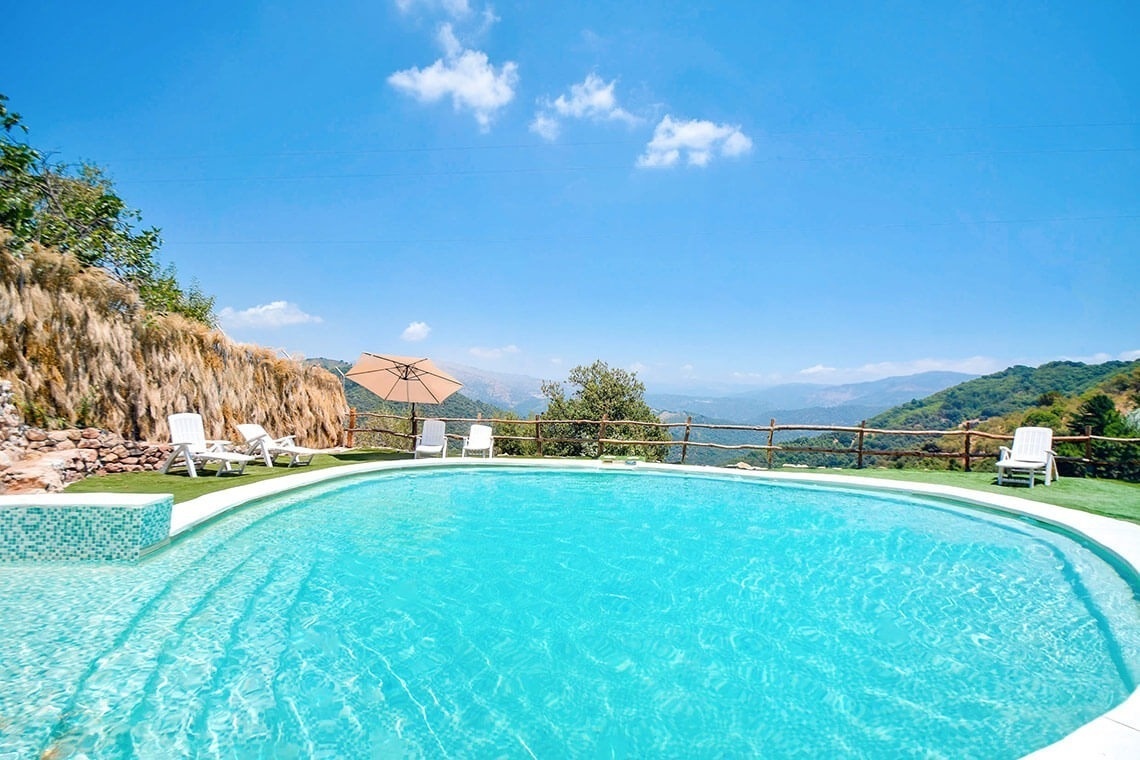 a large swimming pool surrounded by chairs and an umbrella