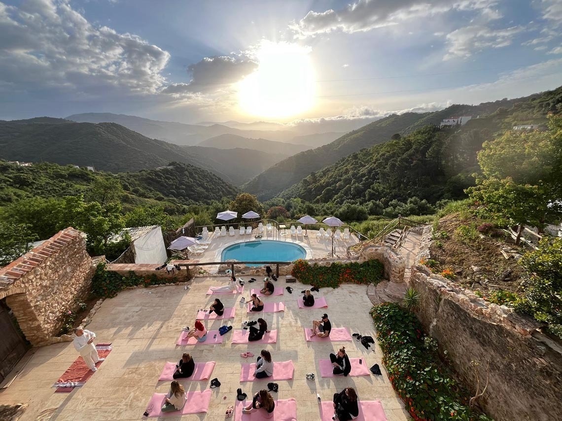 a group of people sit on yoga mats in front of a pool