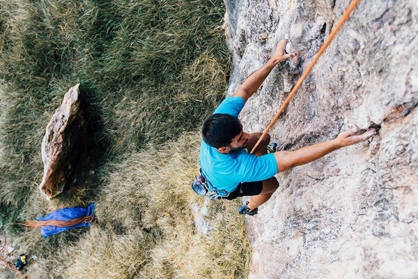 un hombre con una camisa azul está escalando una pared de roca