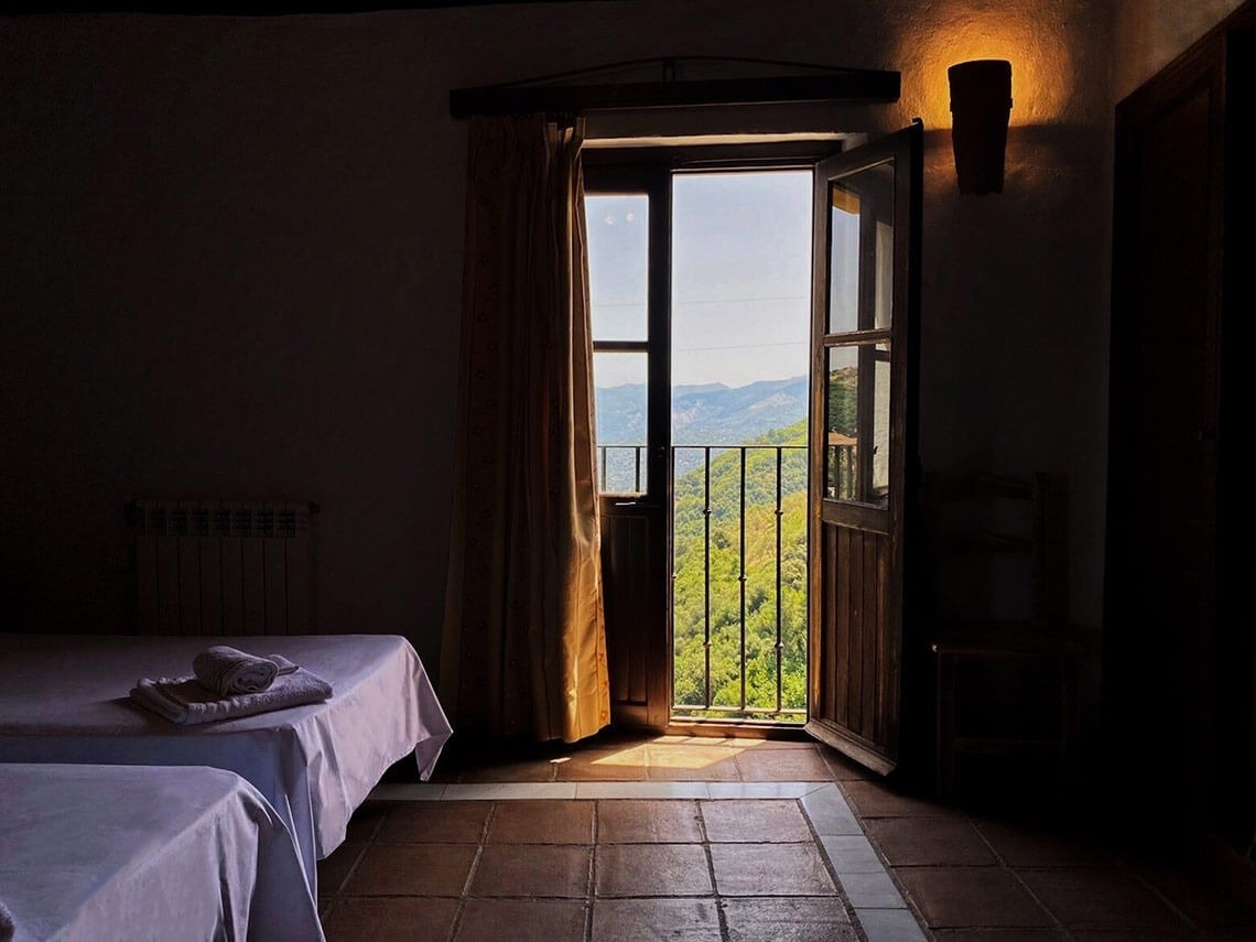 a bedroom with two beds and a balcony with a view of the mountains