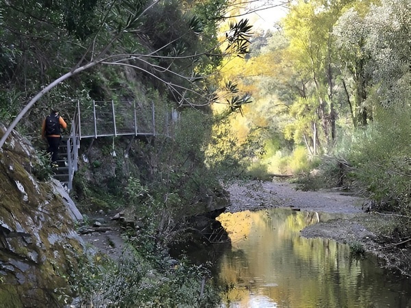 un hombre con una mochila camina por un puente sobre un río