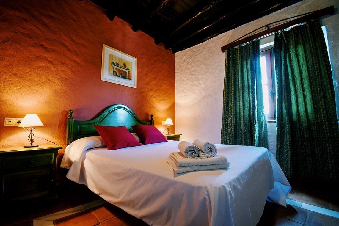 una habitación con una cama y una ventana con cortinas verdes