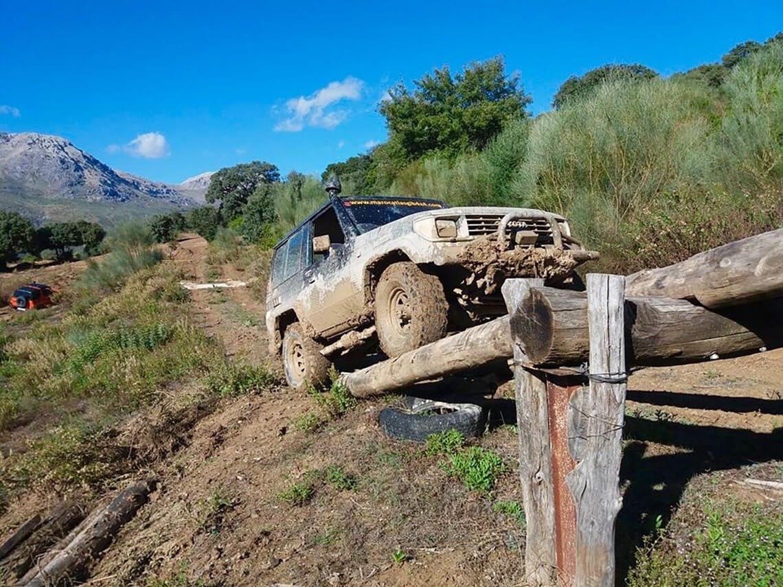 a muddy toyota is driving over a wooden post