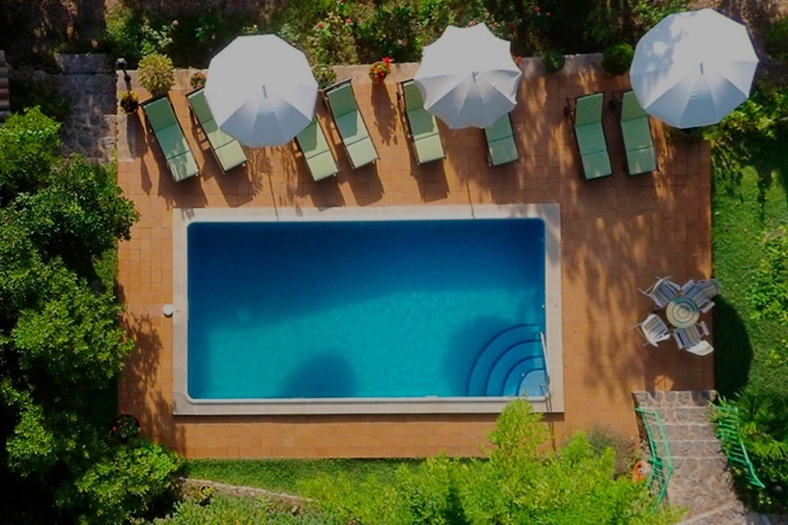 una vista aérea de una piscina rodeada de sillas y sombrillas