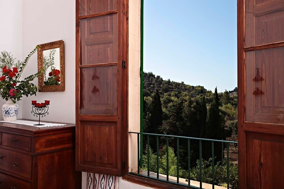 una ventana con persianas de madera y un jarrón de flores