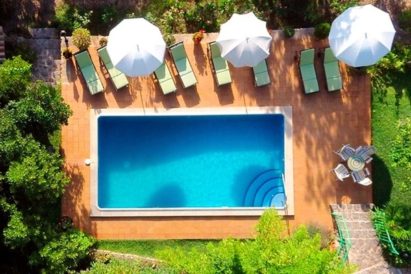 una vista aérea de una piscina rodeada de sillas y sombrillas