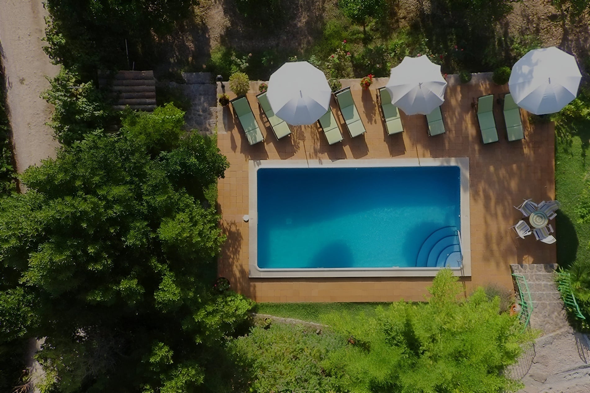 una vista aérea de una piscina rodeada de muebles y sombrillas