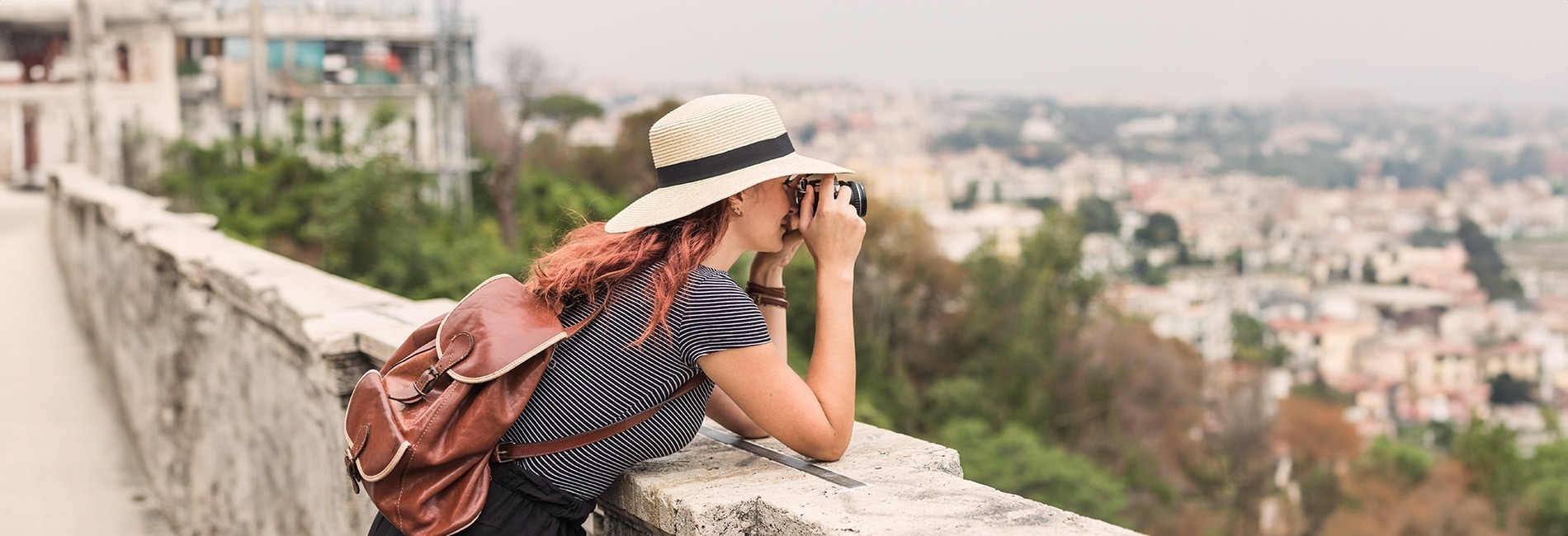 a woman with a backpack is taking a picture of a city
