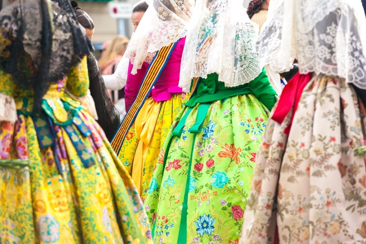 Varias mujeres lucen trajes tradicionales ricamente ornamentados y mantillas de encaje.