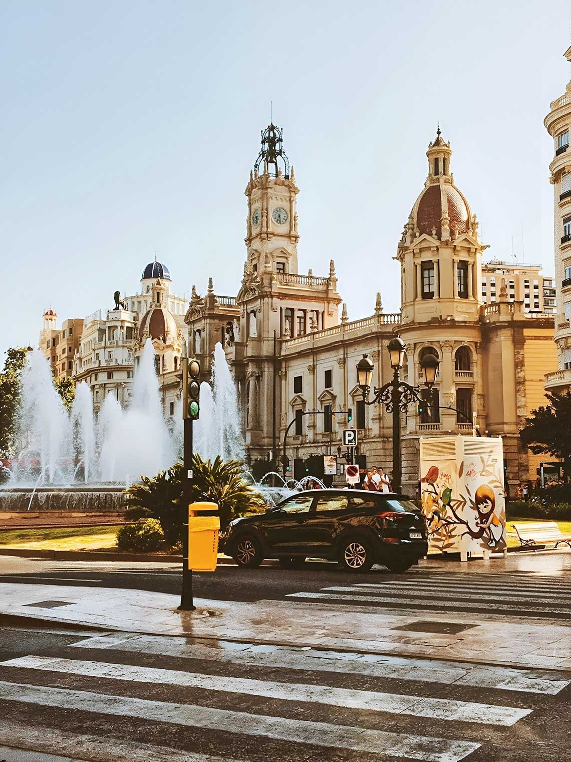 un edificio con una torre de reloj y una fuente en el fondo