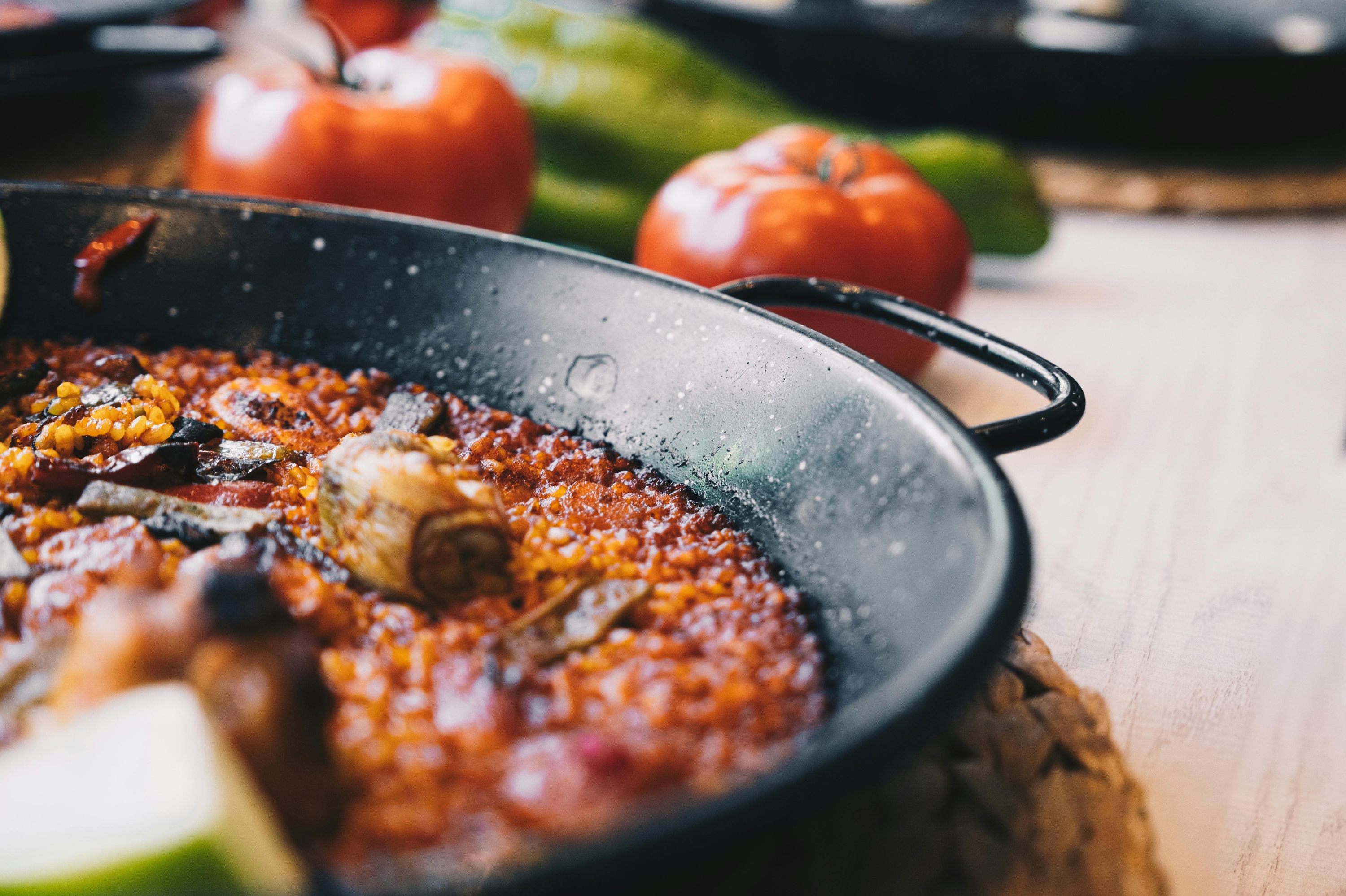 a pan of food with tomatoes and peppers in the background