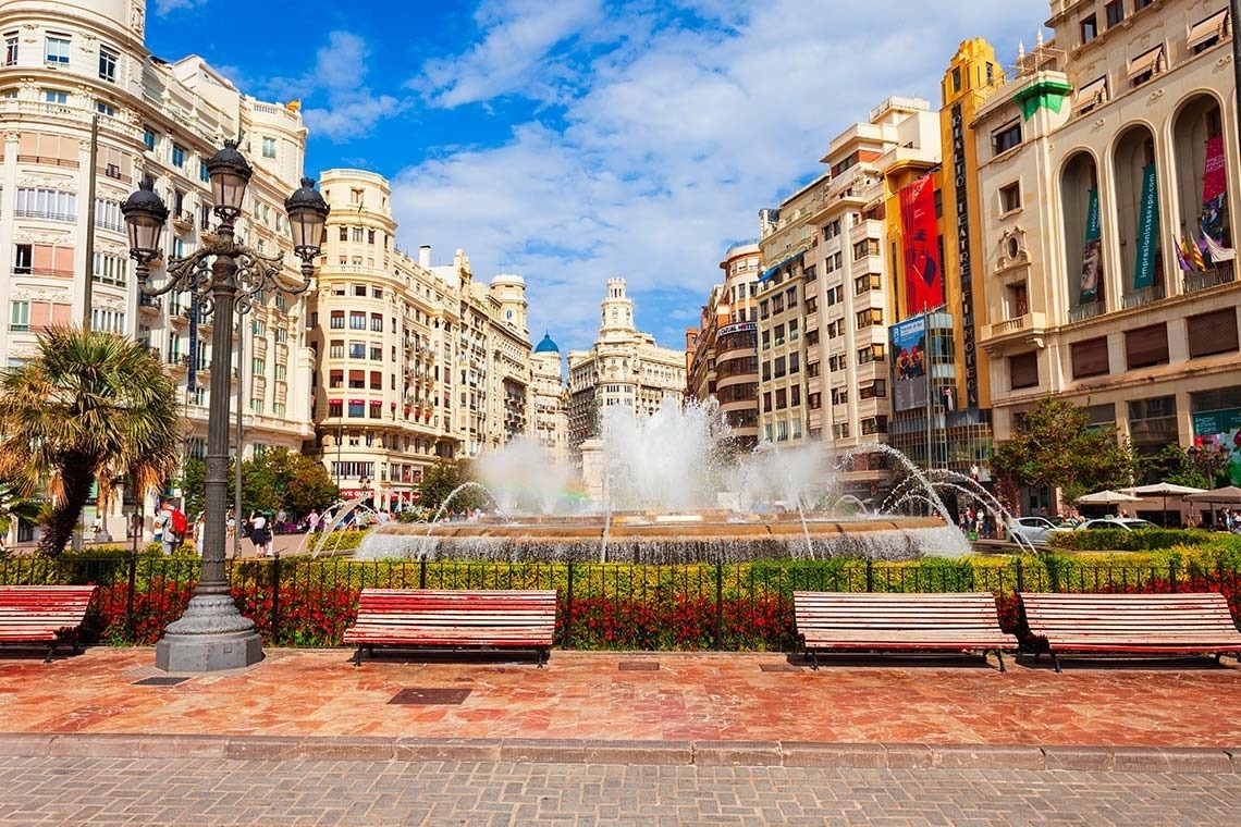 una fuente rodeada de bancos y edificios en una ciudad