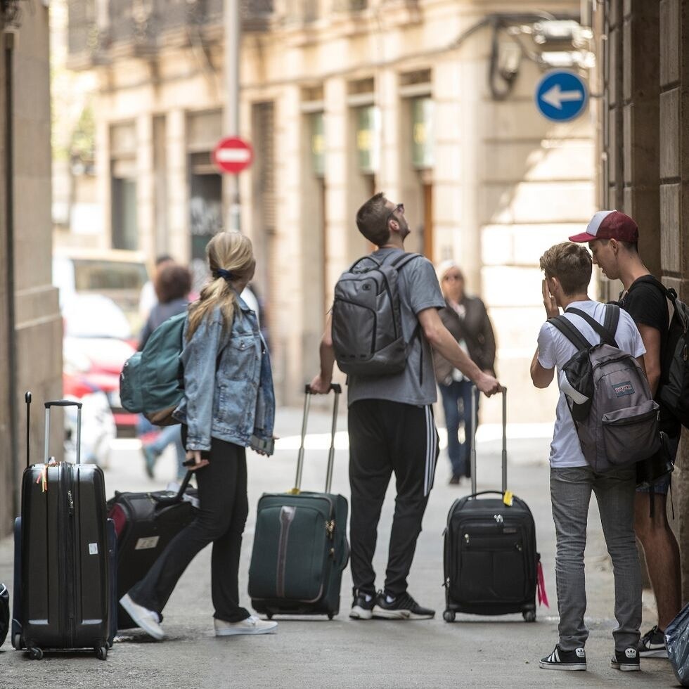 a group of people carrying luggage on a street with an arrow pointing to the right