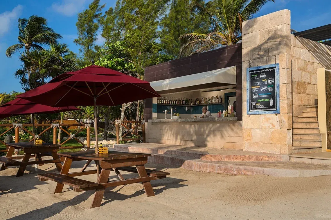 Bar y restaurante en The Fives Corpo, con mesas de picnic en la playa y menú.