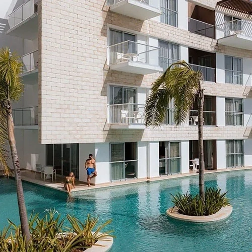The Fives Corpo: Refreshing pool with palm trees in front of a modern hotel.