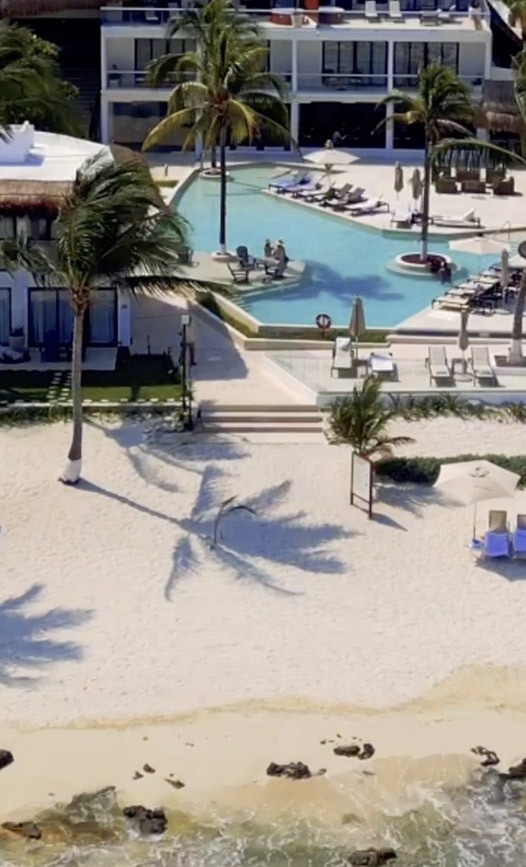 una vista aérea de una playa con palmeras y una gran piscina