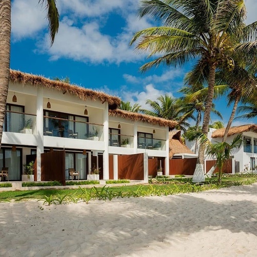 a white building with a thatched roof sits on a sandy beach