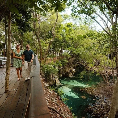 Couple walking on The Fives Corpo wooden path by a cenote.