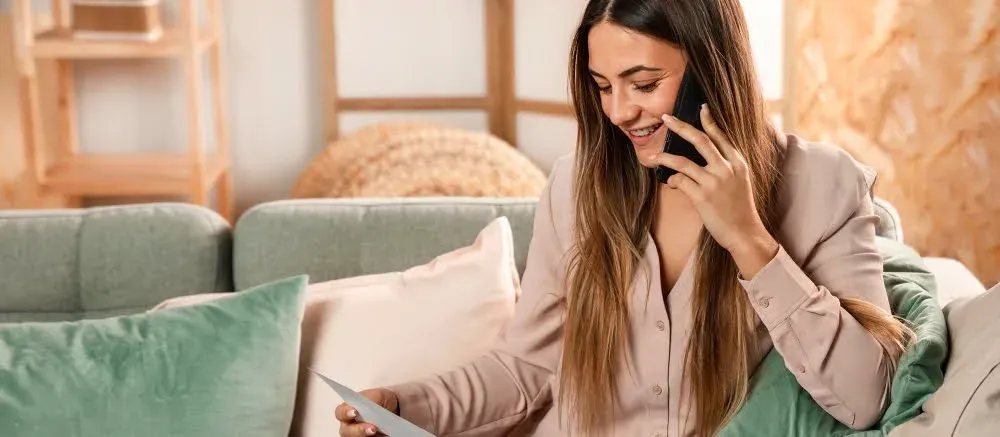 Mujer sonriente en llamada, revisa documentos. Contacto | The Fives Hotels & Residences | México.