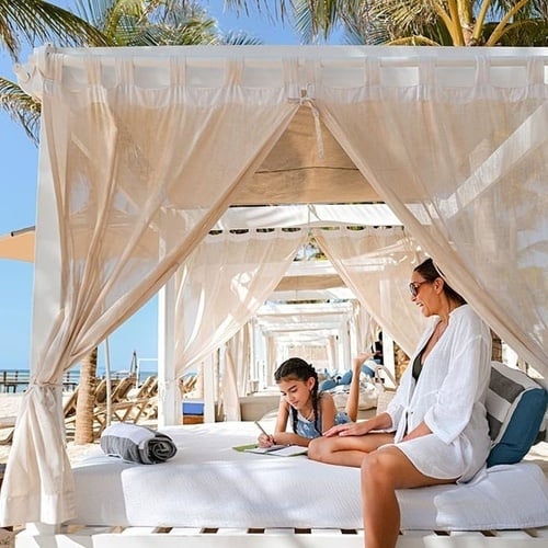 a woman sits on a canopy bed with her daughter