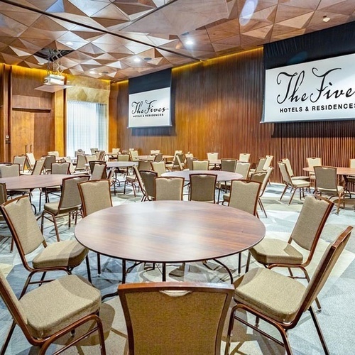 the fives hotel and residences has a large room with tables and chairs
