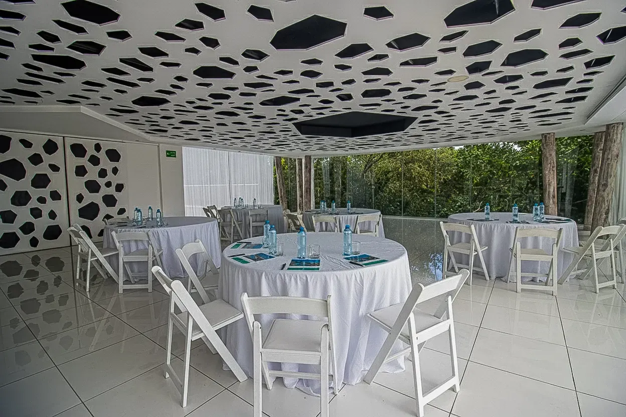 Modern event space with round tables, white chairs, and a uniquely decorated ceiling. The Fives Corpo.