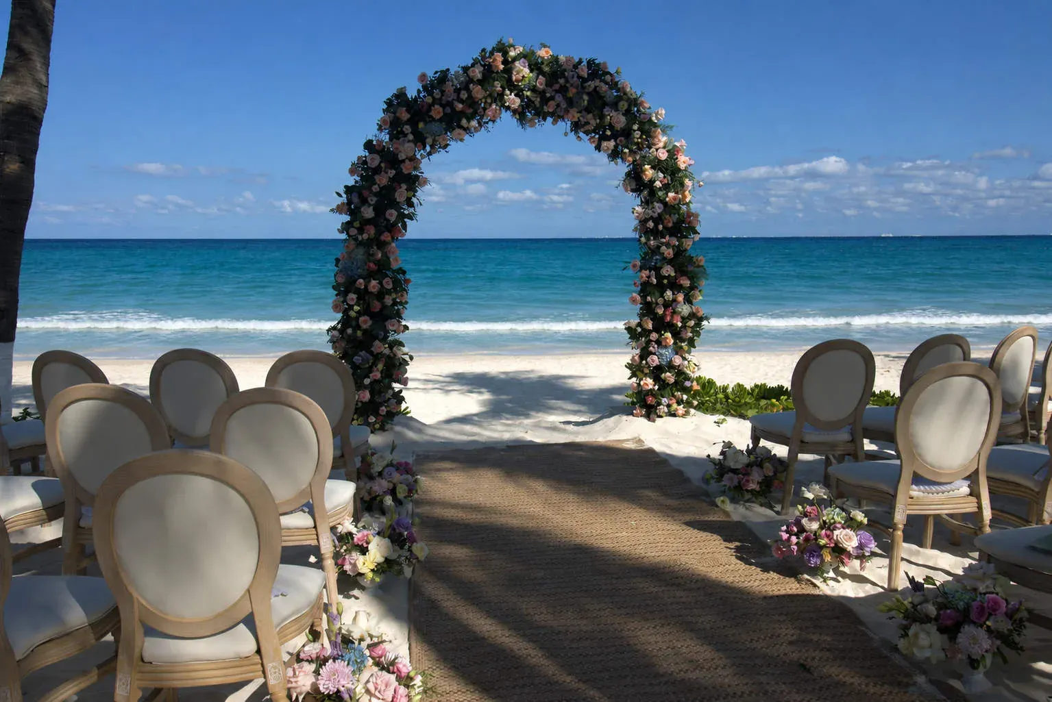 Pasillo de boda en la playa con flores tropicales y vista al mar