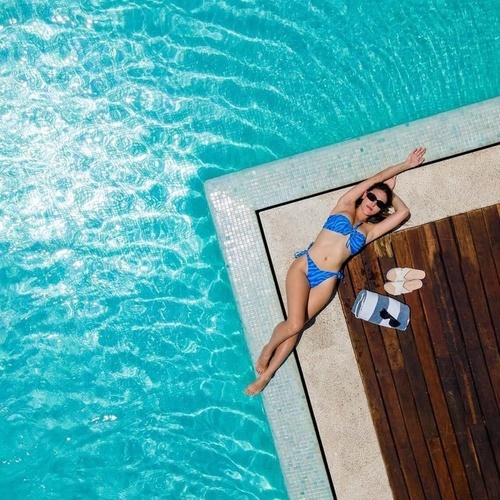 a woman in a blue bikini is laying on the edge of a swimming pool