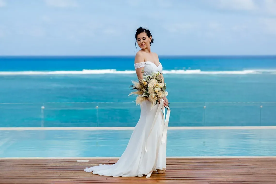 Bride with bouquet at The Fives Corpo, infinity pool, and Caribbean Sea view.