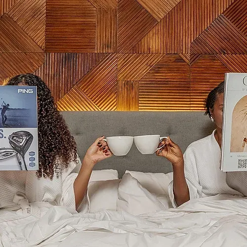 Two women read magazines and drink coffee at The Fives Corpo.