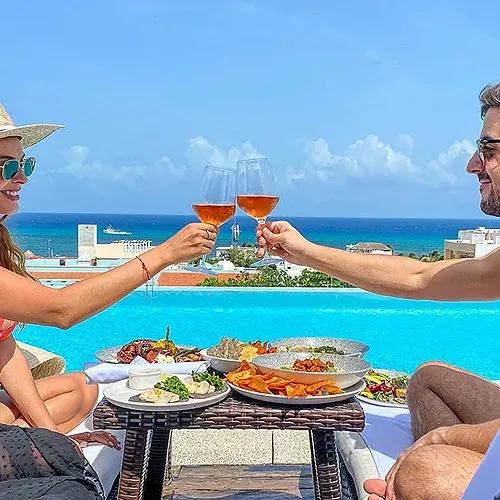 Couple toasting wine by infinity pool at The Fives Corpo, ocean view.
