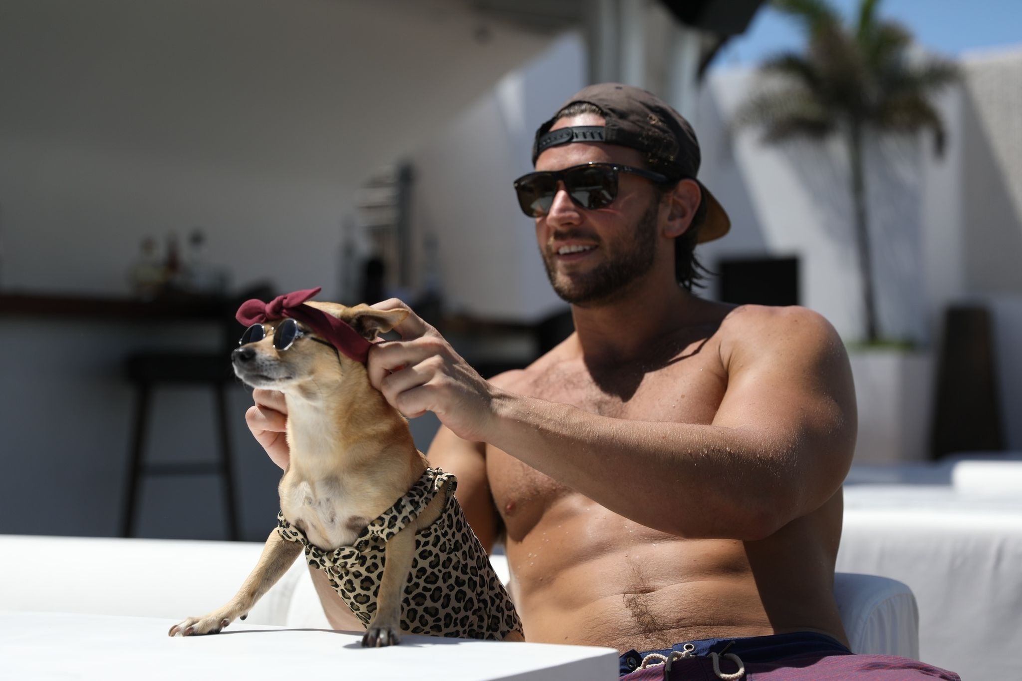 A man adjusts a dog's bandana and sunglasses, a fun scene at Pet Friendly Hotels in Riviera Maya | The Fives Hotels.