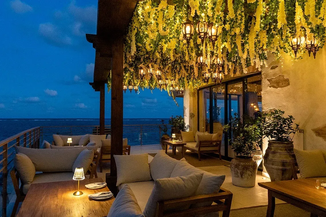 The Fives Corpo hotel terrace with ocean view, lights, plants, and sofas.
