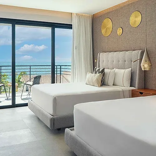 Room with two beds, balcony, and ocean view at The Fives Corpo.
