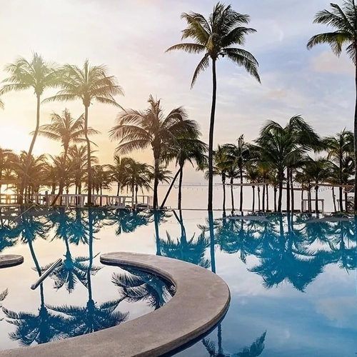 The Fives Corp., tropical sunset pool with palm trees and reflections.