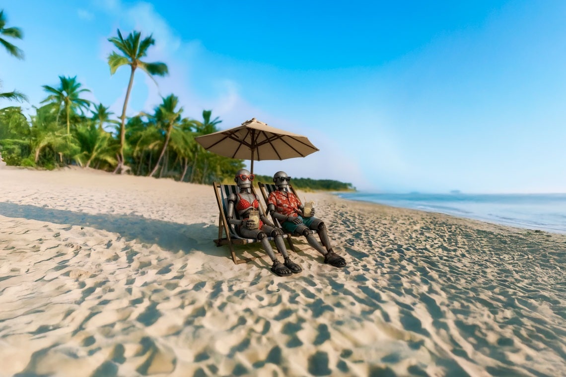 Robots relax under a beach umbrella, enjoying drinks. Cyber Week in Riviera Maya | Up to 40% OFF | The Fives Hotels.