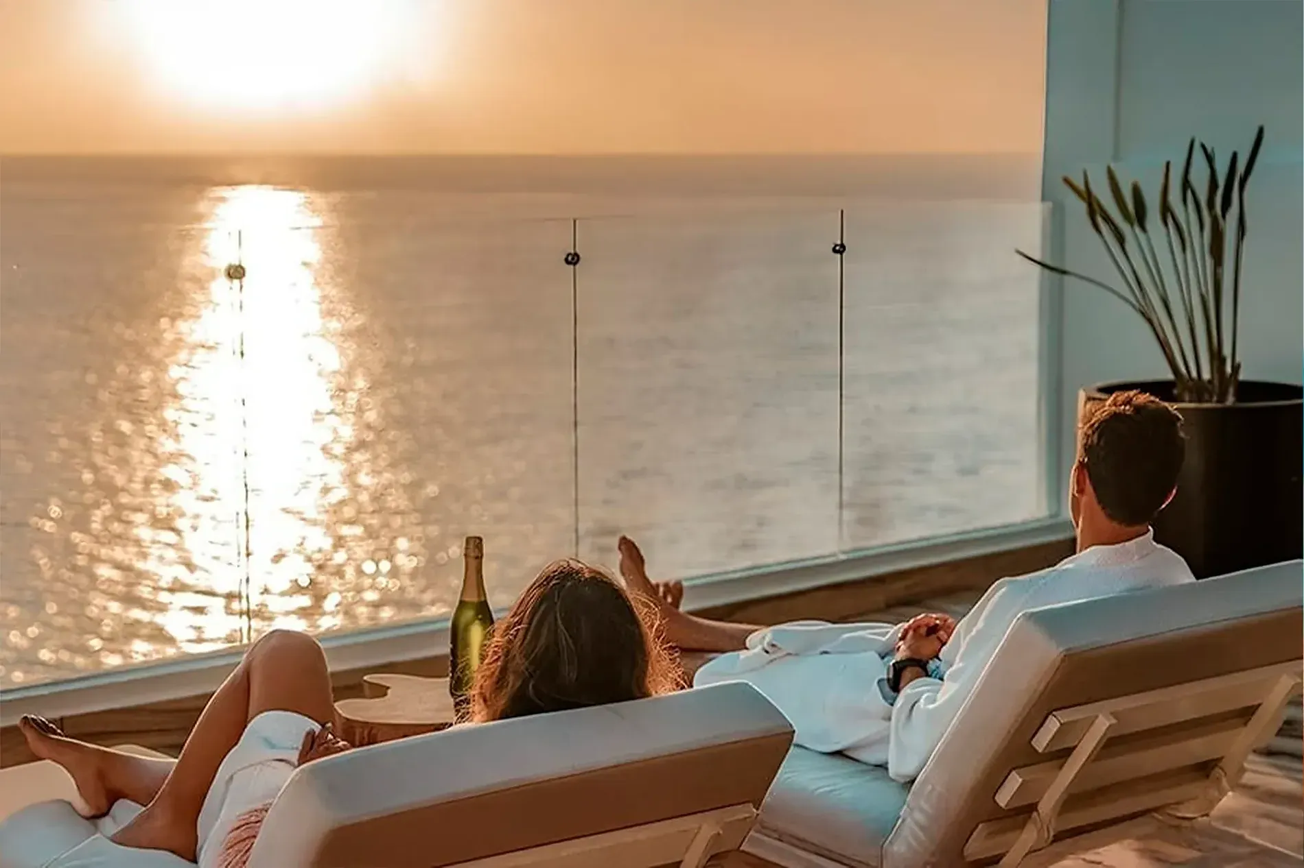 Pareja relajándose en The Fives Corpo con vistas al mar y sol.