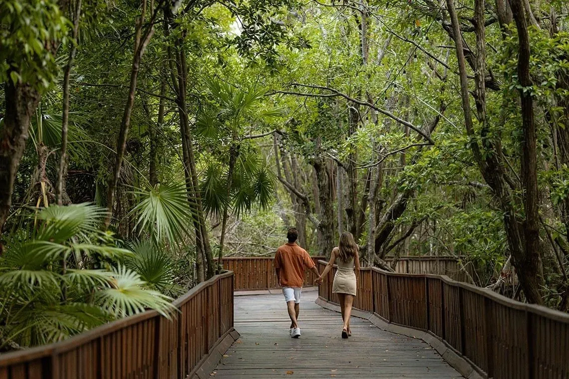 Pareja paseando de la mano en el sendero de The Fives Beach Hotel, México.