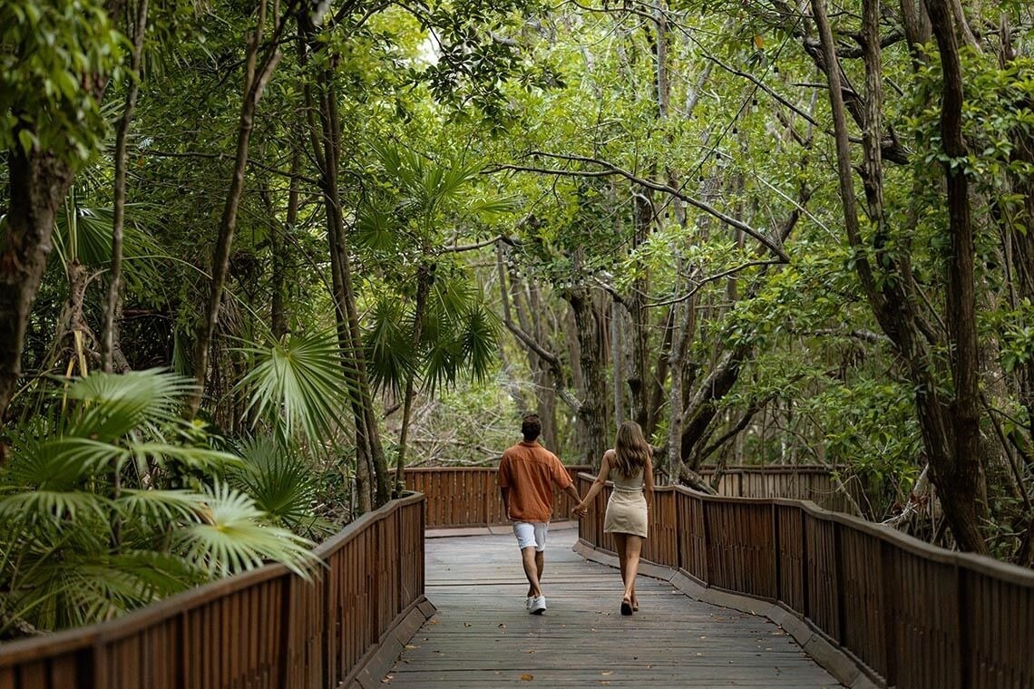 Couple strolls on boardwalk at The Fives Beach Hotel, Mexico.