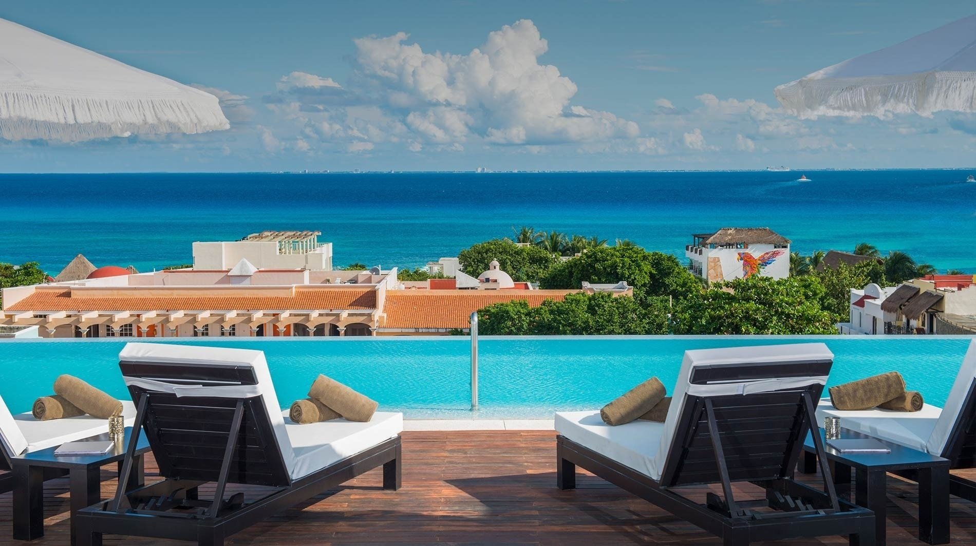 una vista del océano desde una piscina con sillas y sombrillas