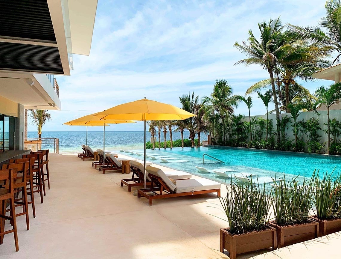 Disfruta The Fives Oceanfront Riviera Maya - Todo Incluido Opcional: Piscina infinita, playa y palmeras.