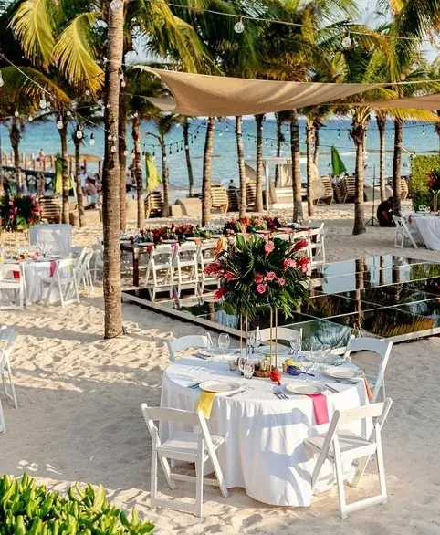 Beach banquet at The Fives Corpo: white tables, tropical flowers, and the Caribbean Sea.