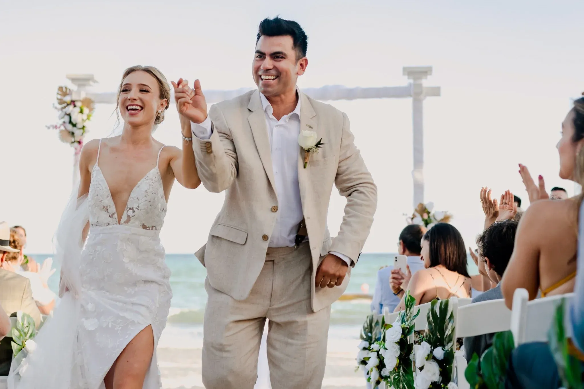 Happy bride and groom celebrating their beach wedding The Fives Corpo reception with guests.
