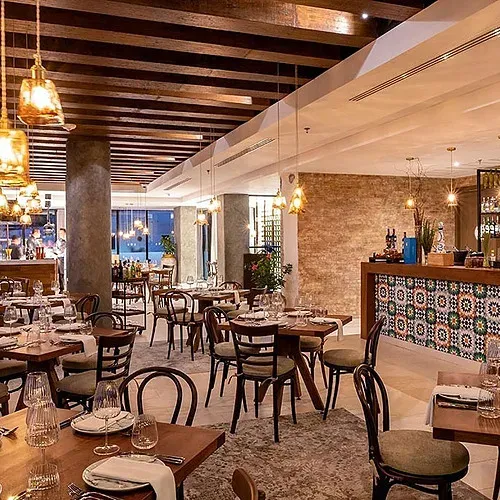 The Fives Corpo's elegant dining room, featuring golden pendant lights and set tables.