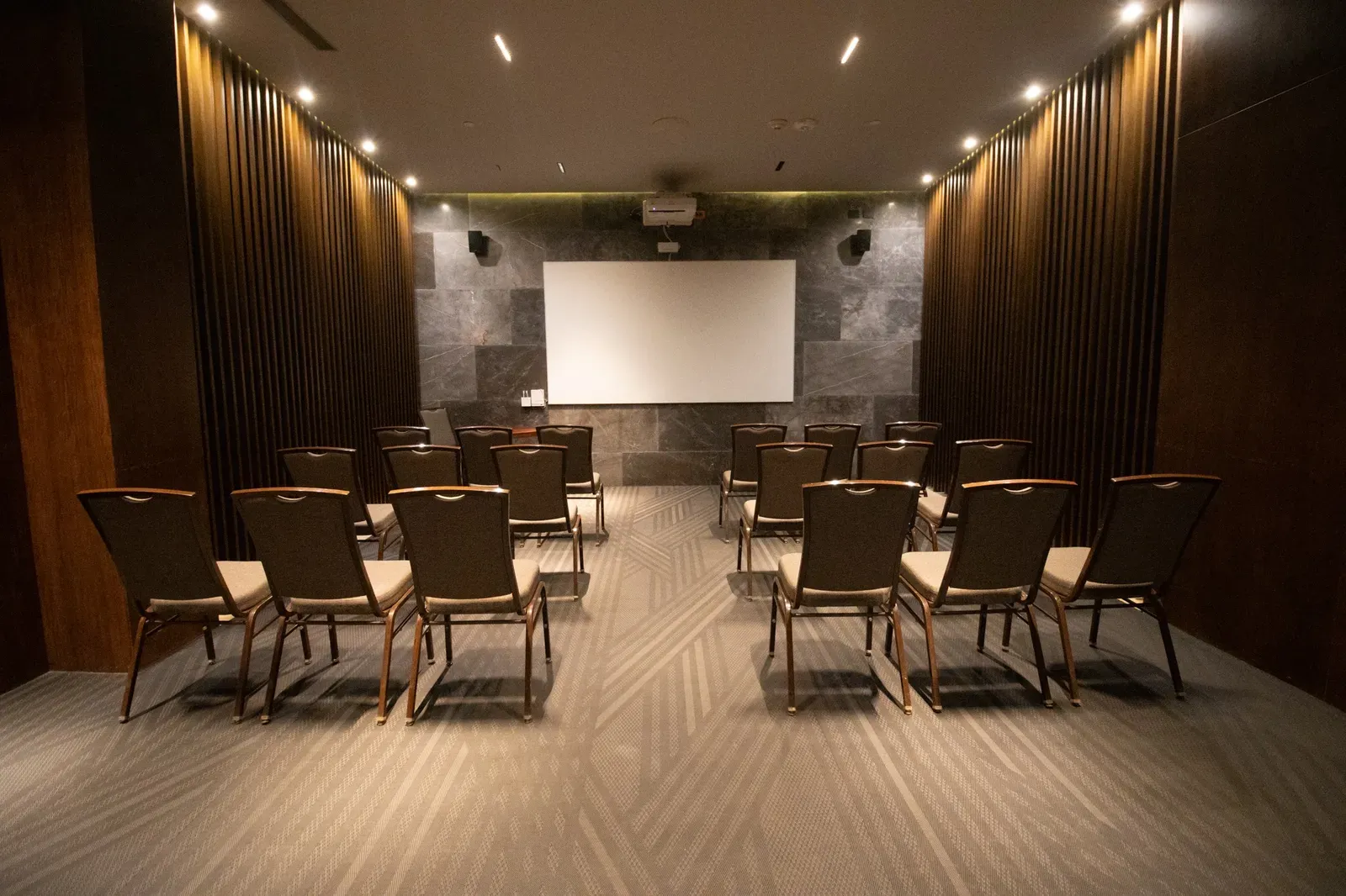 The Fives Corpo: Conference room with theater seating, projector, and screen.