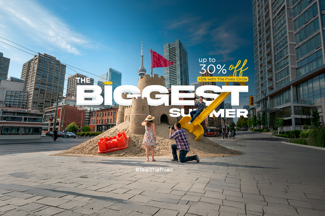 A giant yellow rubber duck stands prominently in front of London's Big Ben and Houses of Parliament, surrounded by people taking photos, advertising "The Biggest Summer" with "up to 30% off".