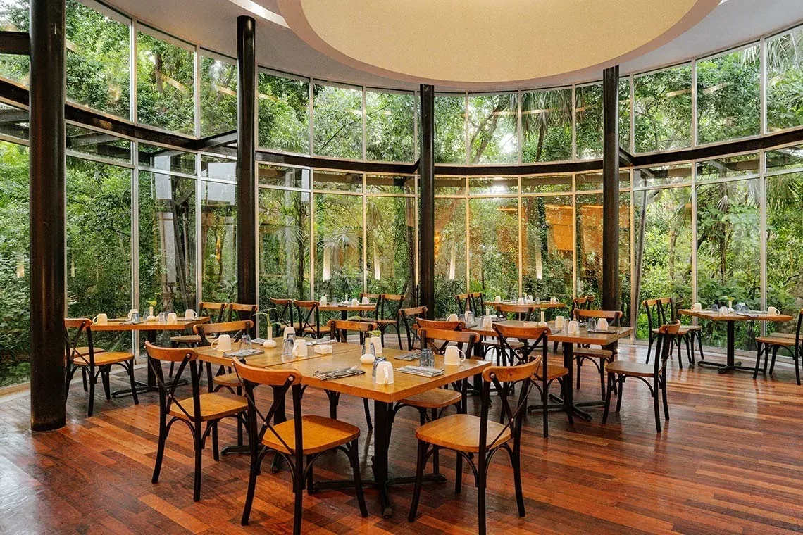 El restaurante The Fives Corpo con vistas al jardín tropical, mesas listas.